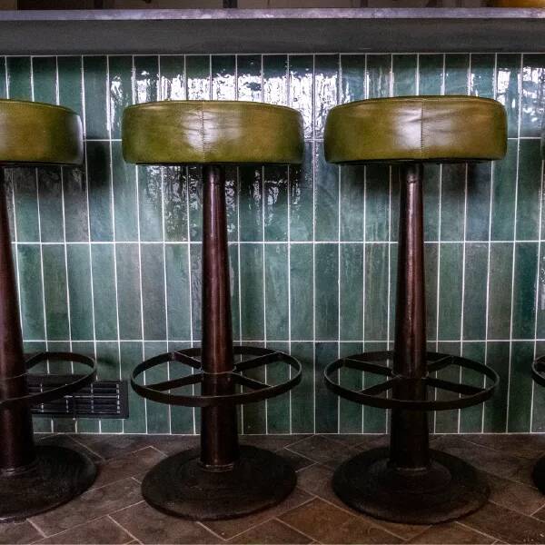 green tiled kitchen island with industrial bar stools