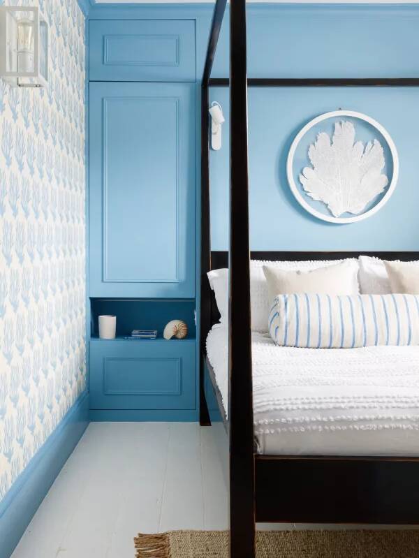 blue bedroom with black fourposter bed and white linen